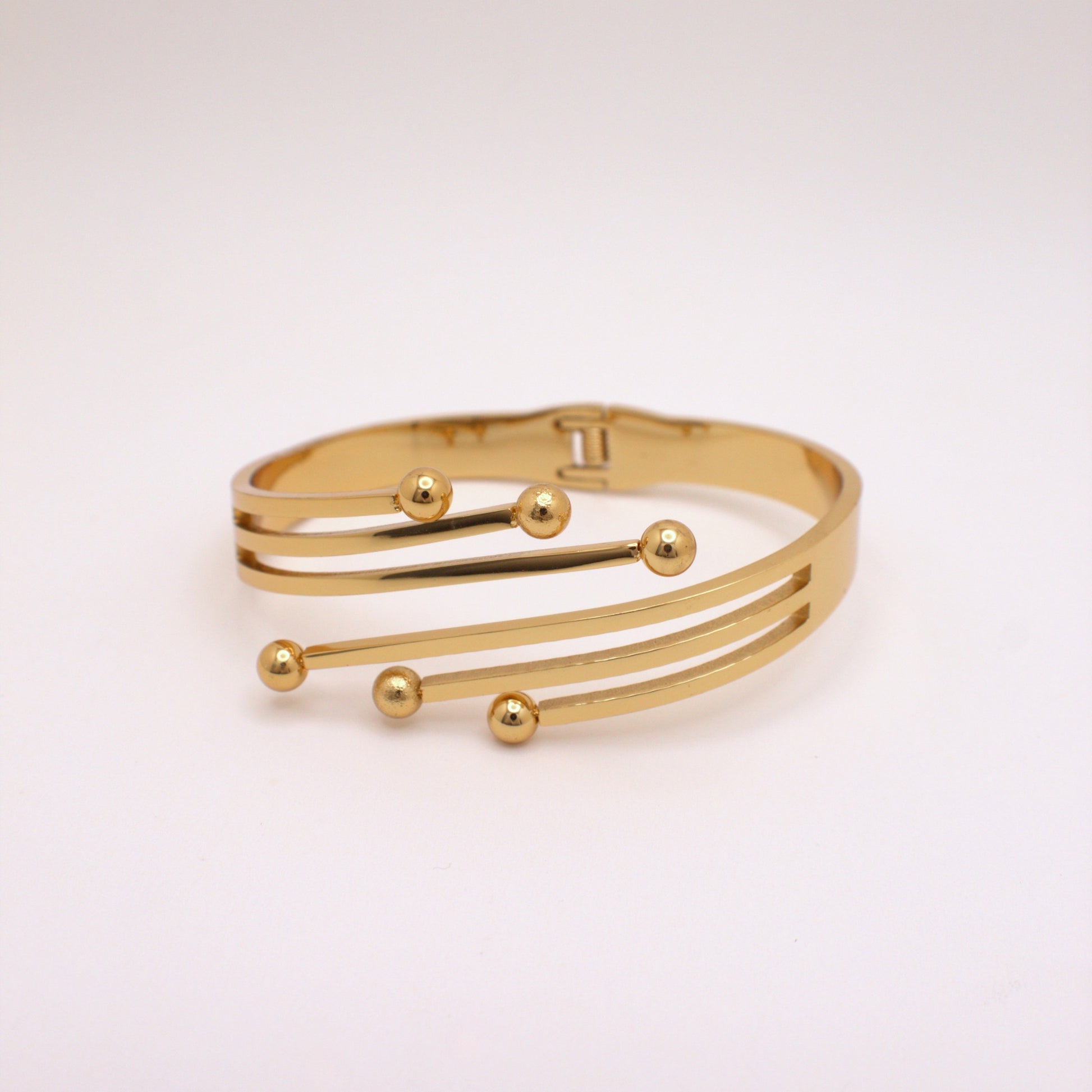 Gold bracelet with spherical accents on a light pink background