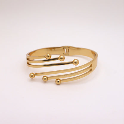Gold bracelet with spherical accents on a light pink background