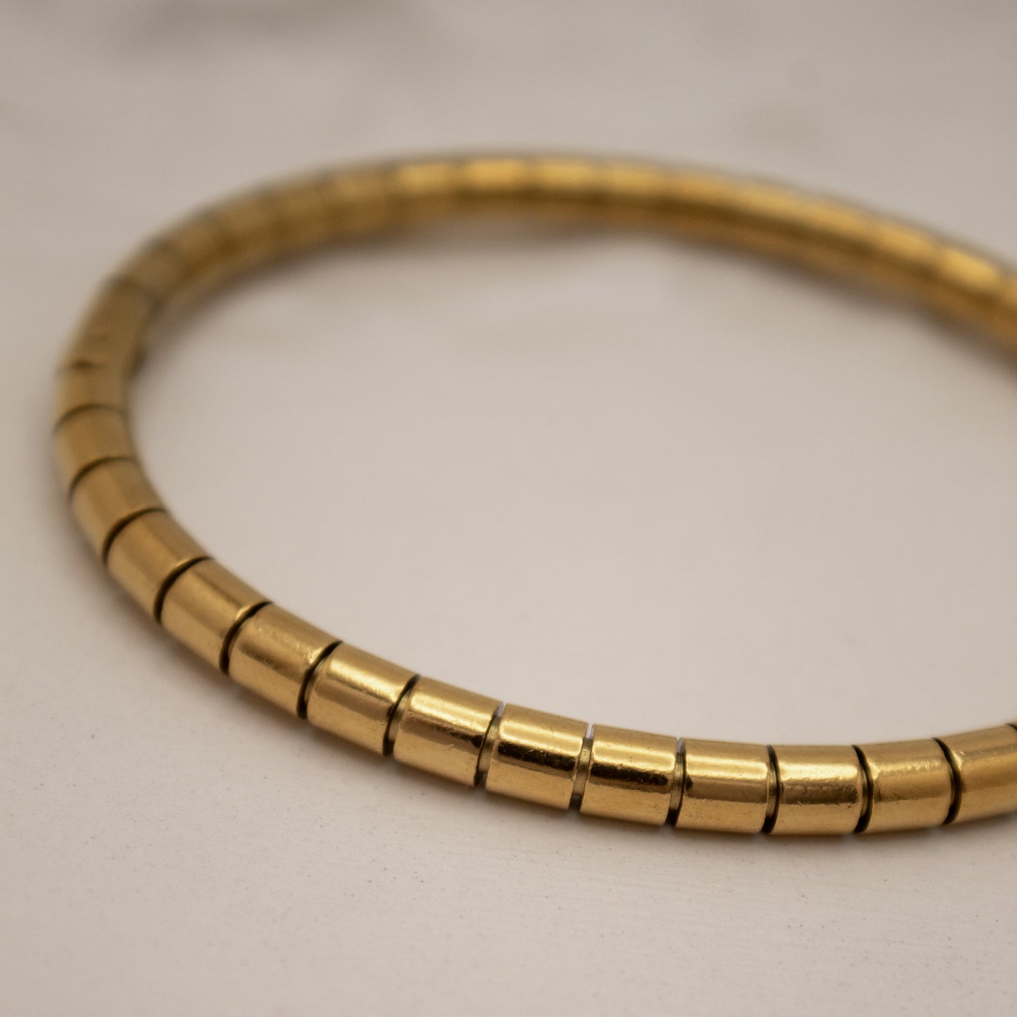 Gold beaded bracelet on a light gray background