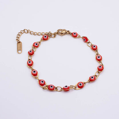 Gold chain bracelet with red evil eye beads, shown on a plain white background. The clasp and extender chain are visible, and the brand name 'SARAI' is engraved on the tag.