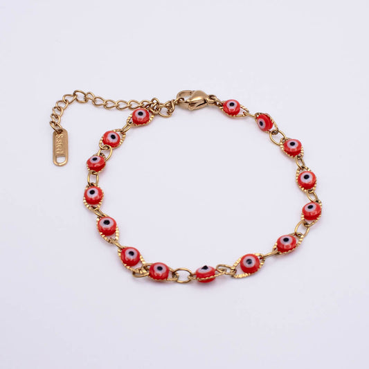 Gold chain bracelet with red evil eye beads, shown on a plain white background. The clasp and extender chain are visible, and the brand name 'SARAI' is engraved on the tag.