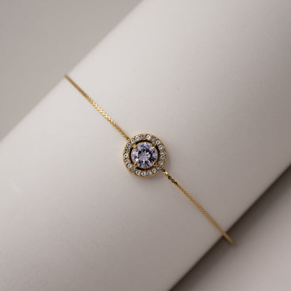 Gold bracelet with a central gemstone on a neutral background
