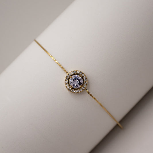 Gold bracelet with a central gemstone on a neutral background