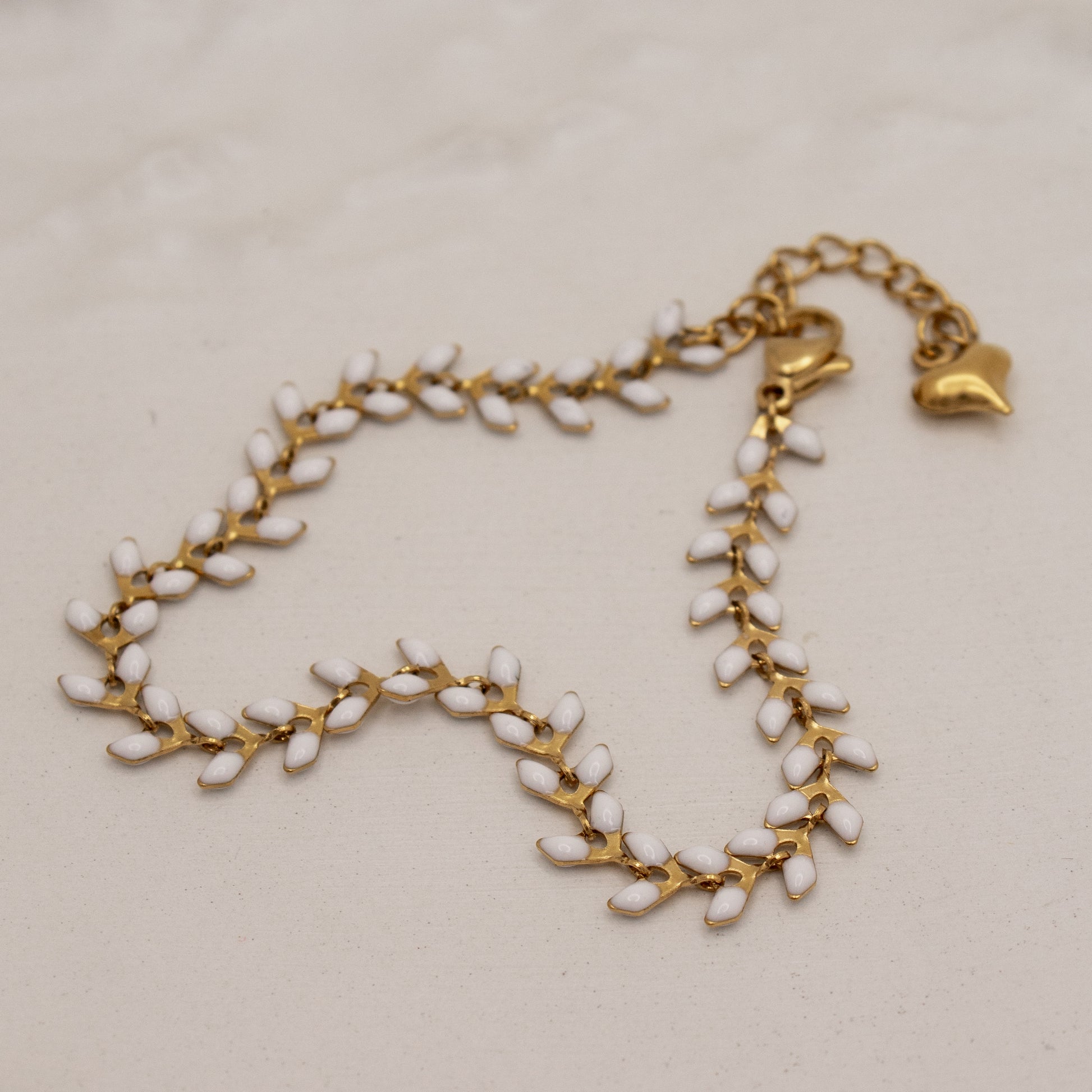 Gold and white beaded necklace on a beige background