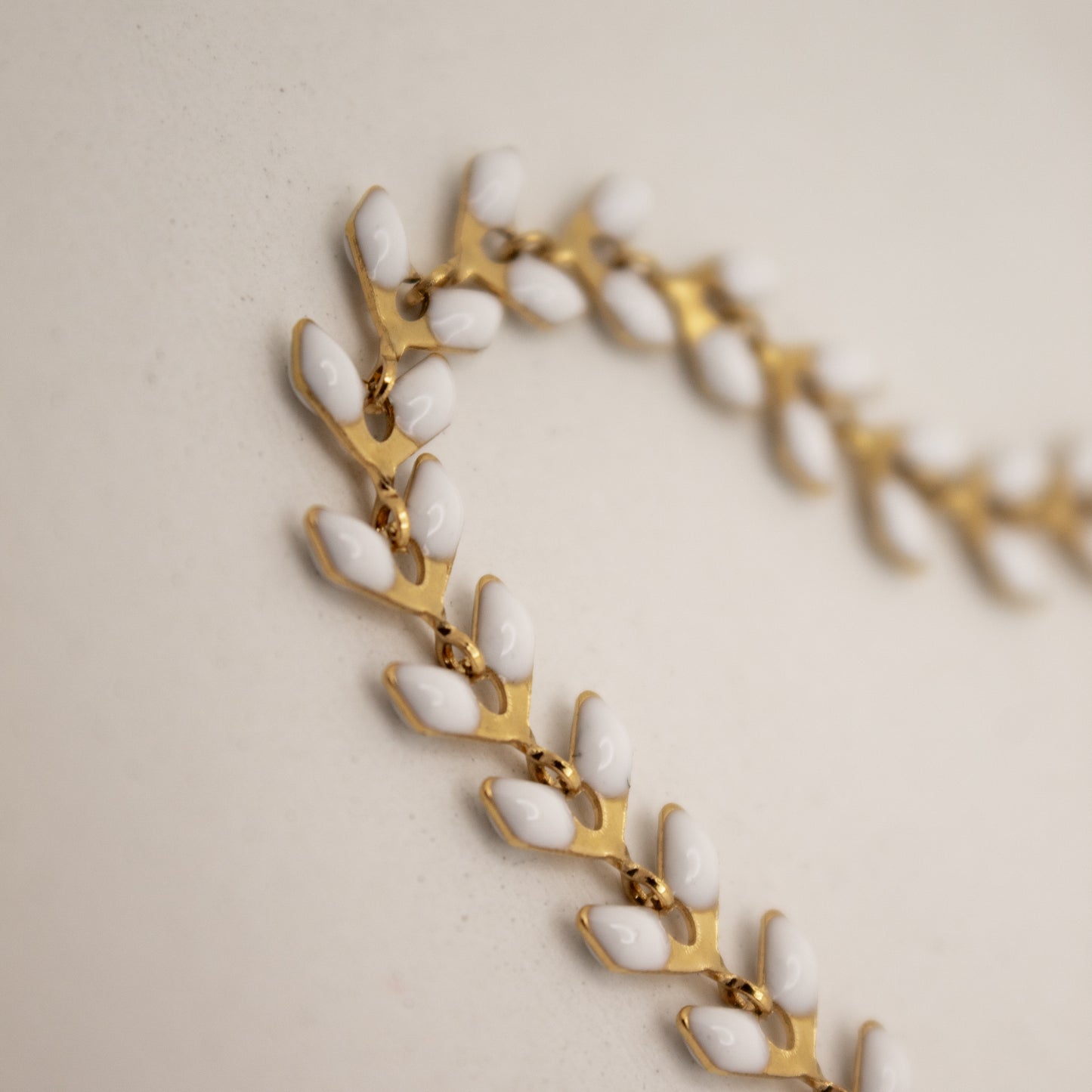 Bracelet with gold and white beads on a beige background