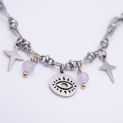 A silver-toned chain necklace featuring a central oval charm with an eye design, flanked by two lavender beads with gold spacer beads and two silver star charms, on a plain white background.