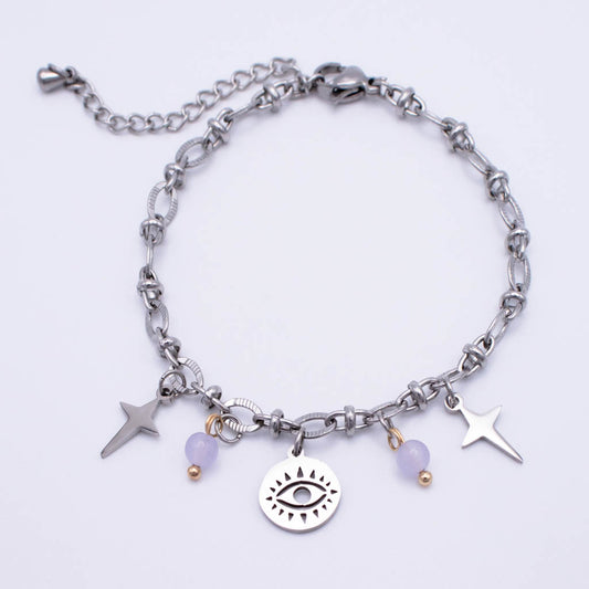 A silver-toned chain anklet featuring a central round charm with an eye design, flanked by two star charms, a small purple bead, and a tiny gold bead. The anklet is displayed on a clean white background.