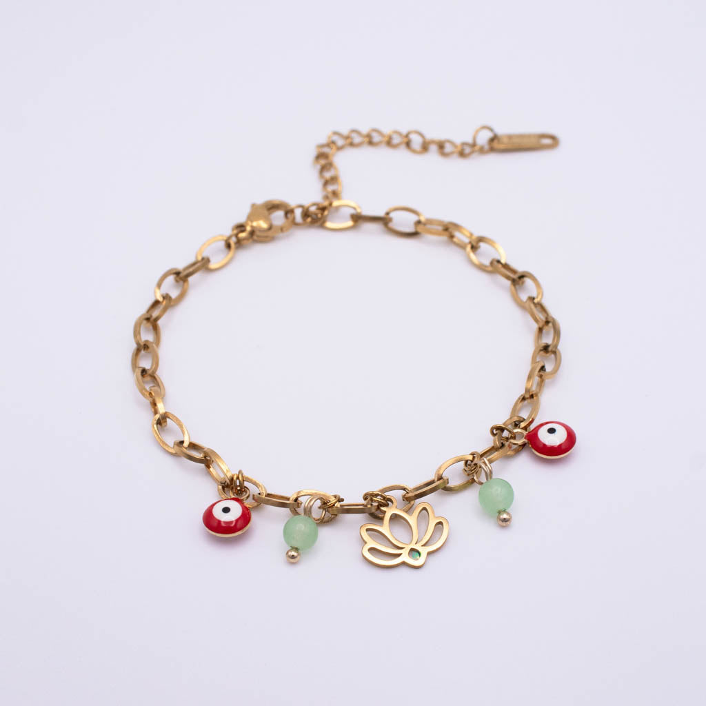 A gold chain bracelet with evil eye charms, a gold butterfly charm, and two light green beads, displayed on a clean white background.