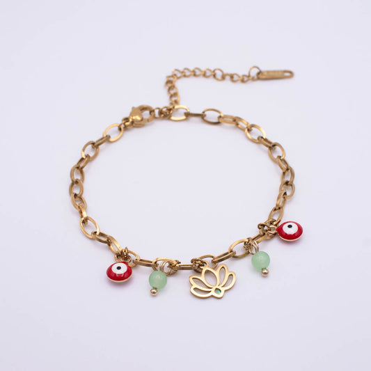 A gold chain bracelet with evil eye charms, a gold butterfly charm, and two light green beads, displayed on a clean white background.