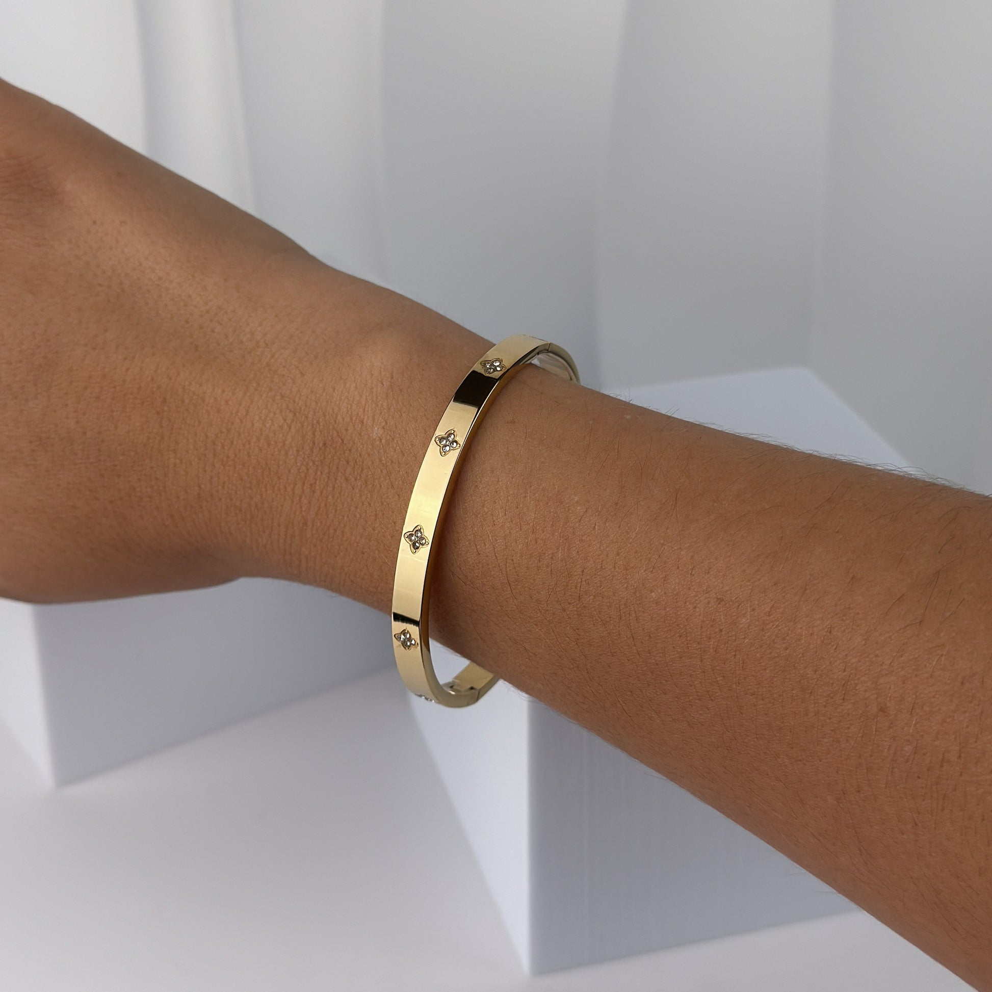 Gold bracelet on a person's wrist against a white background
