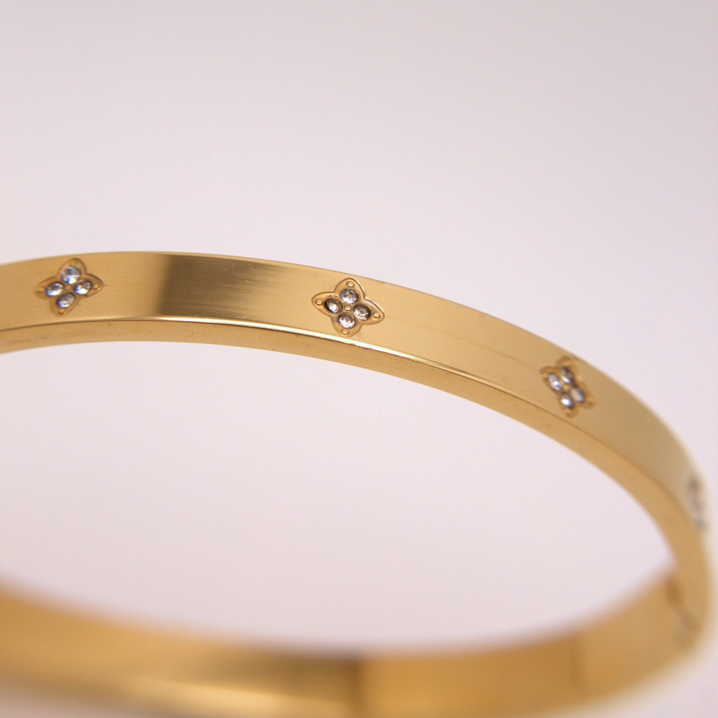 Gold bracelet with floral designs on a white background