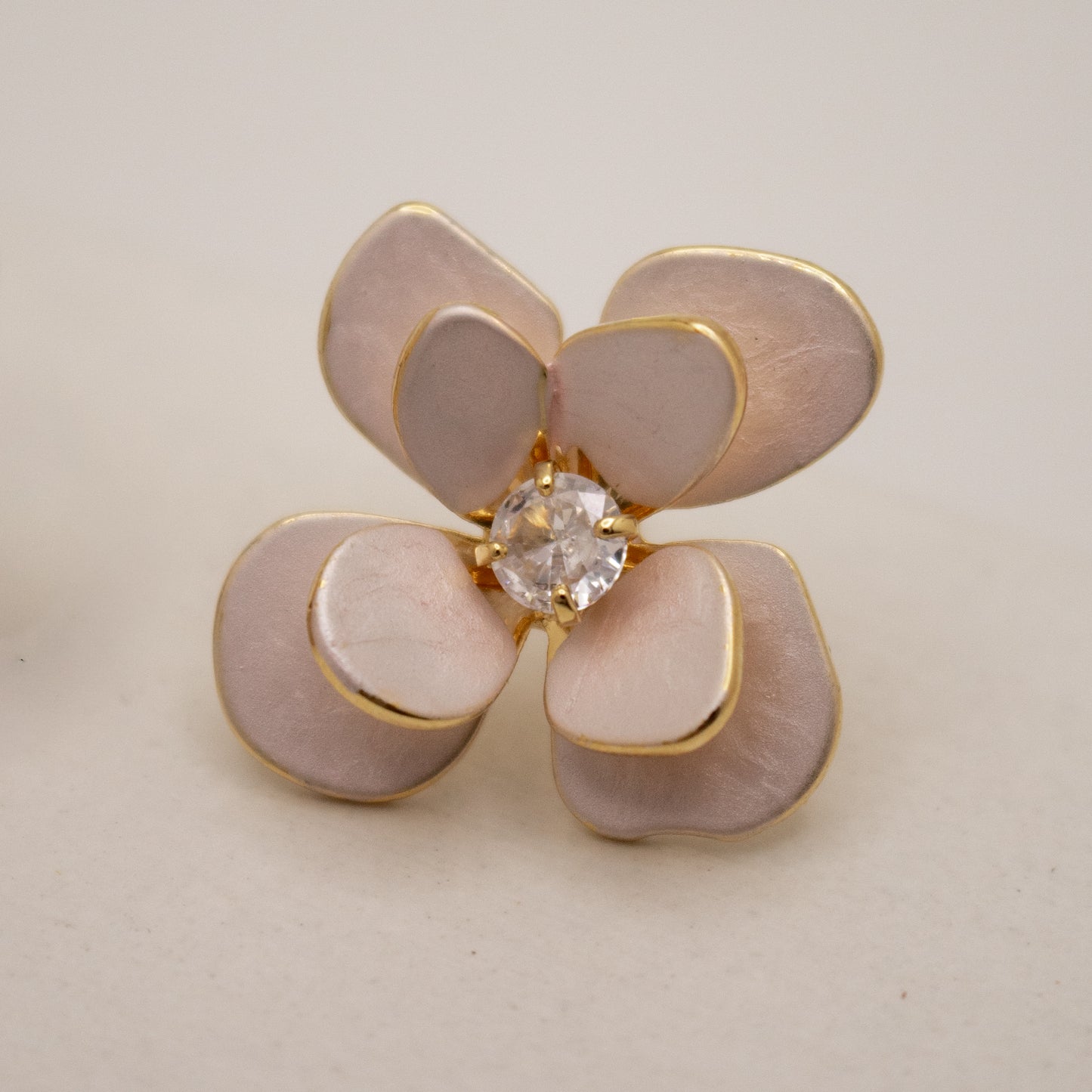 Floral-shaped earring with a central gemstone on a beige background