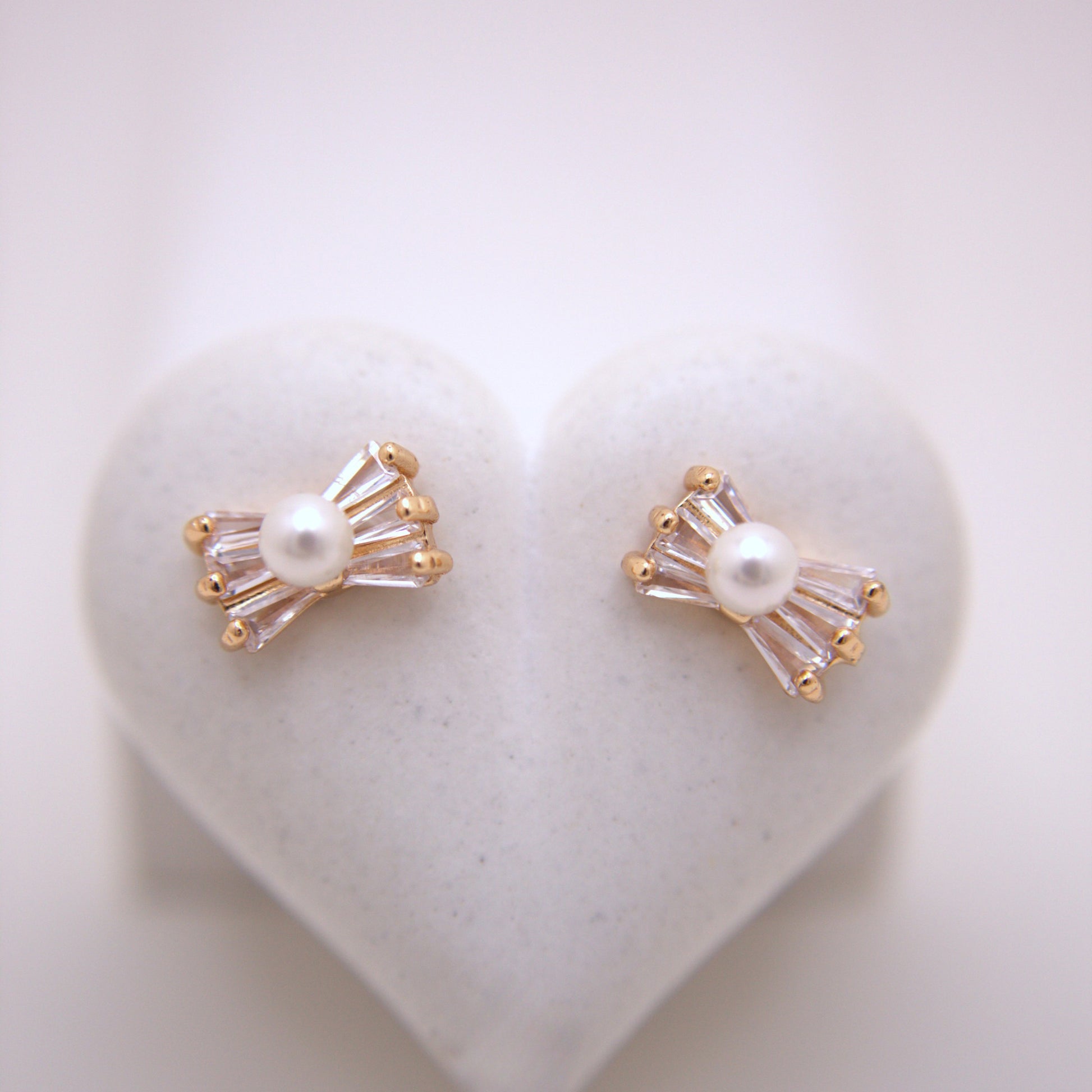 Pair of pearl earrings with gold accents on a heart-shaped white stone