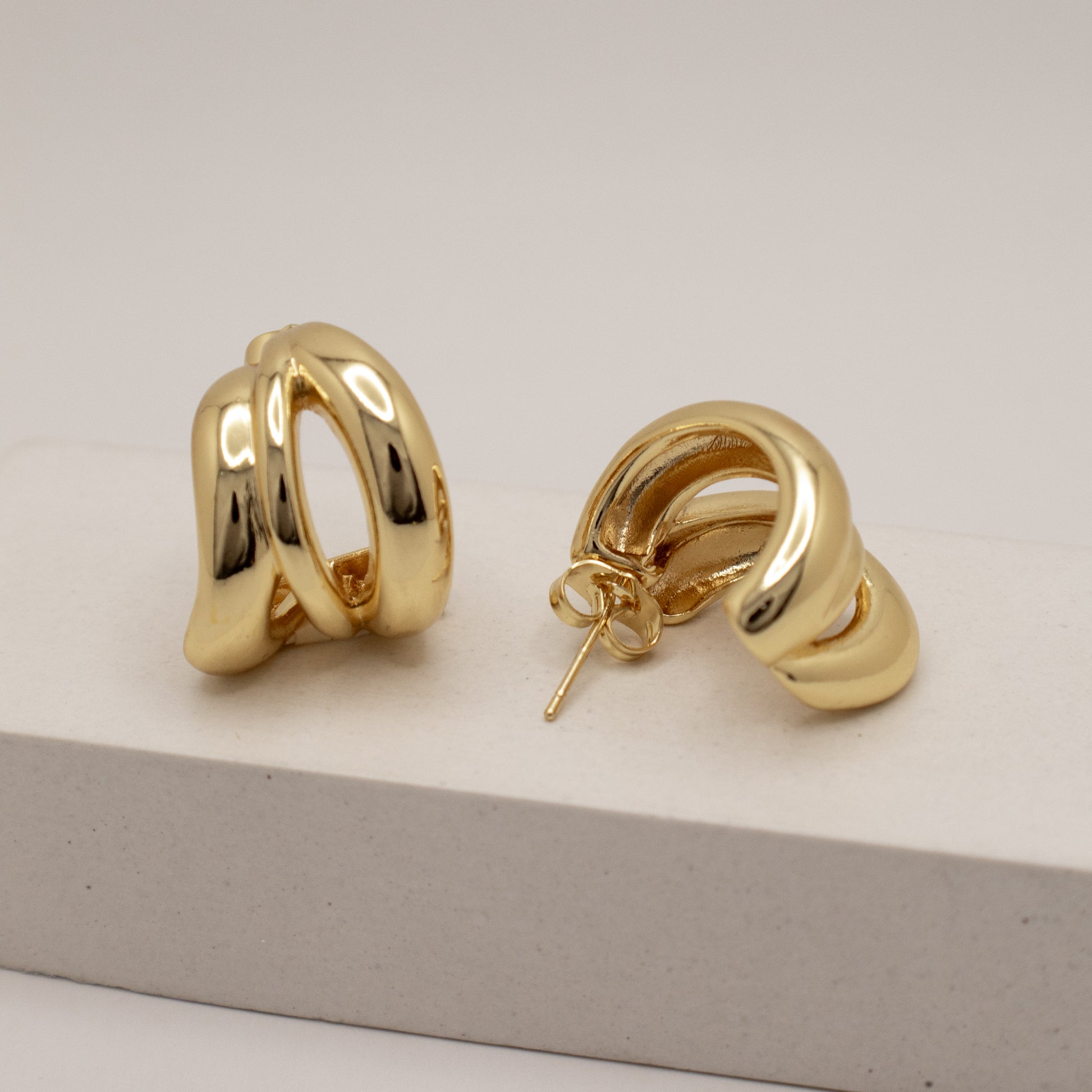 Gold hoop earrings on a light gray surface