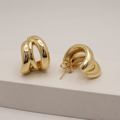 Gold hoop earrings on a light gray surface