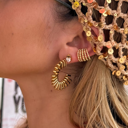 Close-up of a person wearing gold hoop earrings with a decorative headband.