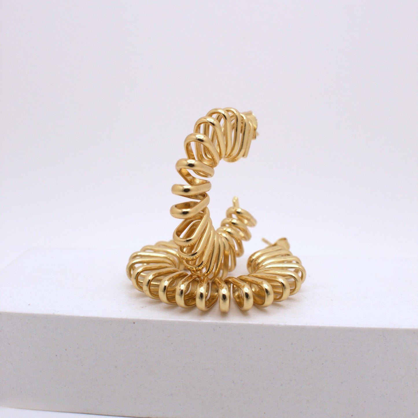 Gold spiral earring on a white background