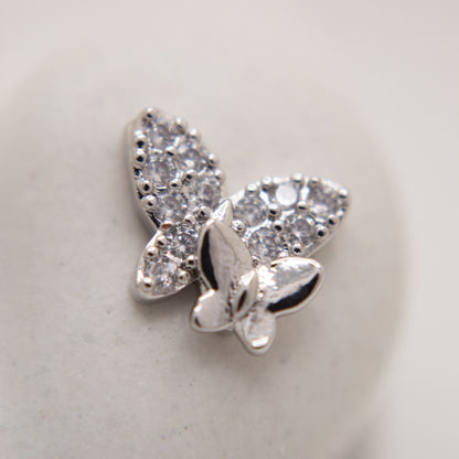 Silver butterfly-shaped earring with clear gemstones on a light gray background