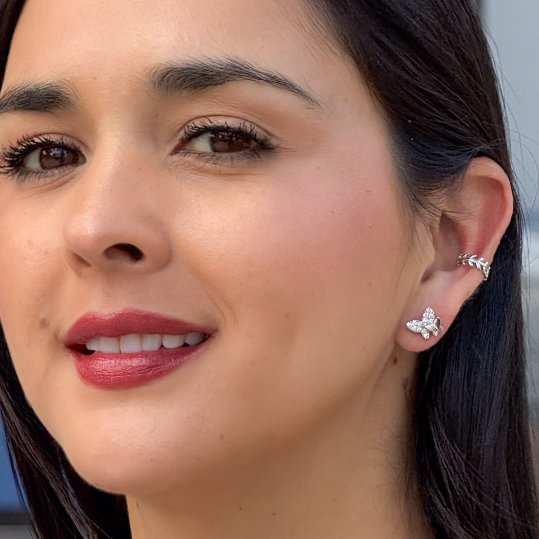 Close-up of a woman wearing butterfly earrings with a blurred background