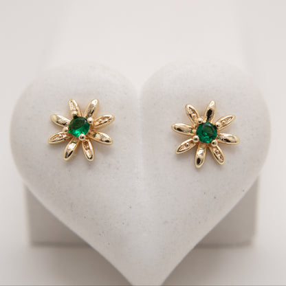 Gold earrings with green gemstones on a heart-shaped stand