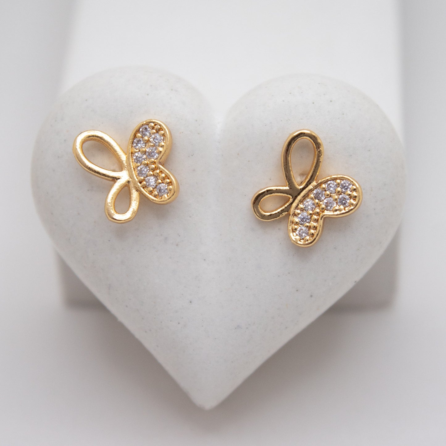 Gold butterfly earrings on a heart-shaped white stone