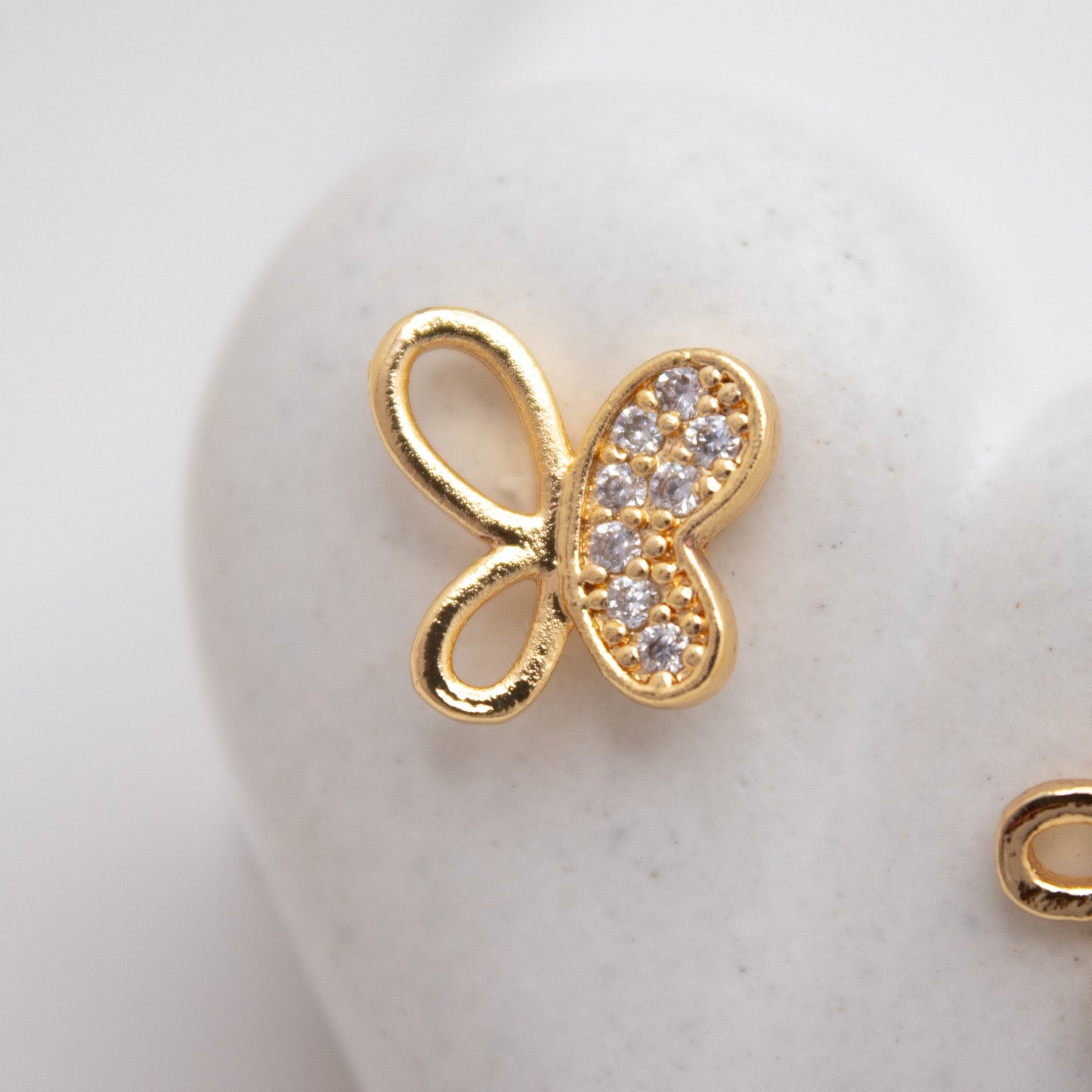 Gold butterfly earrings with clear stones on a white background