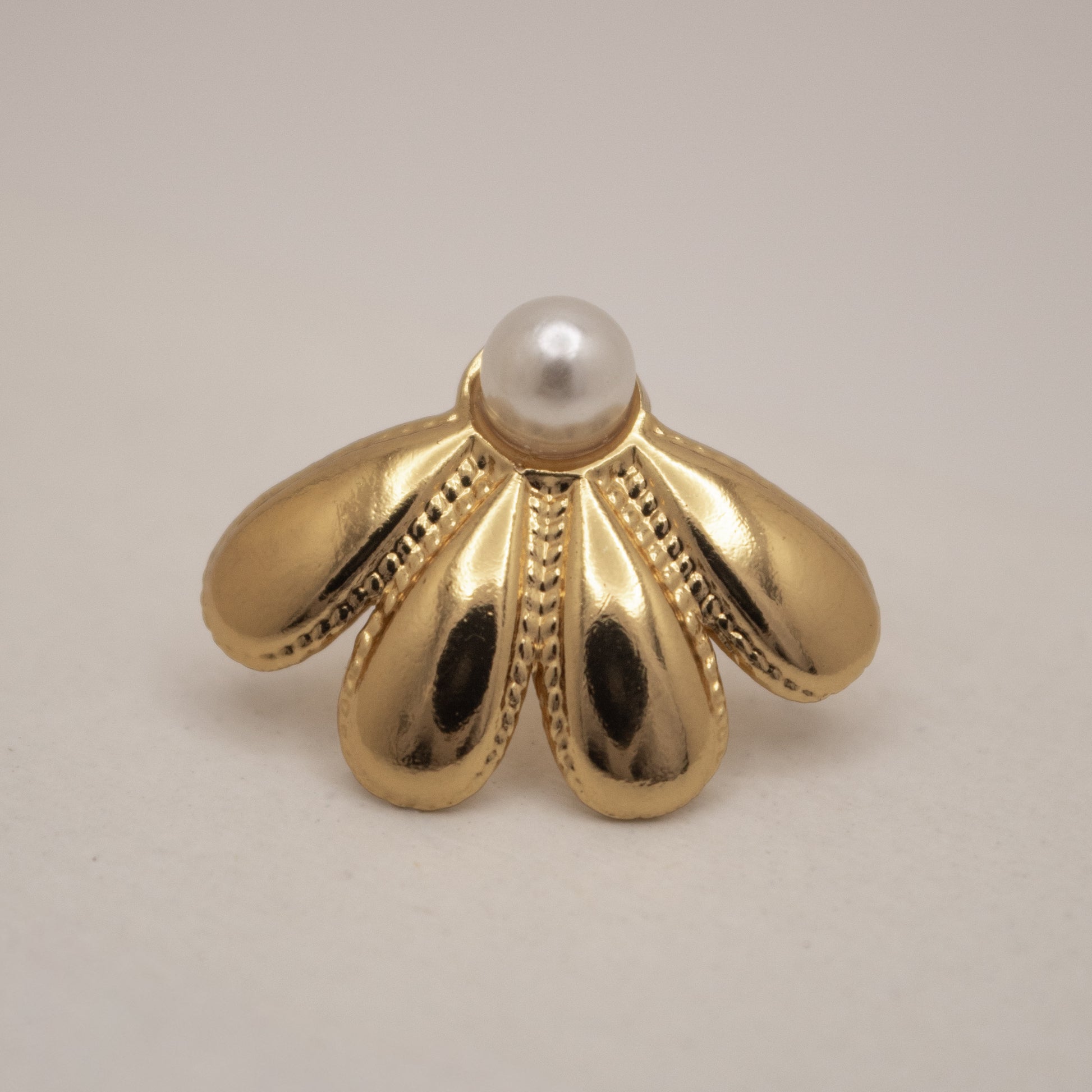 Gold earring with a pearl on a beige background