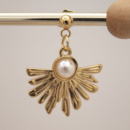 Gold earring with a pearl center on a gray background