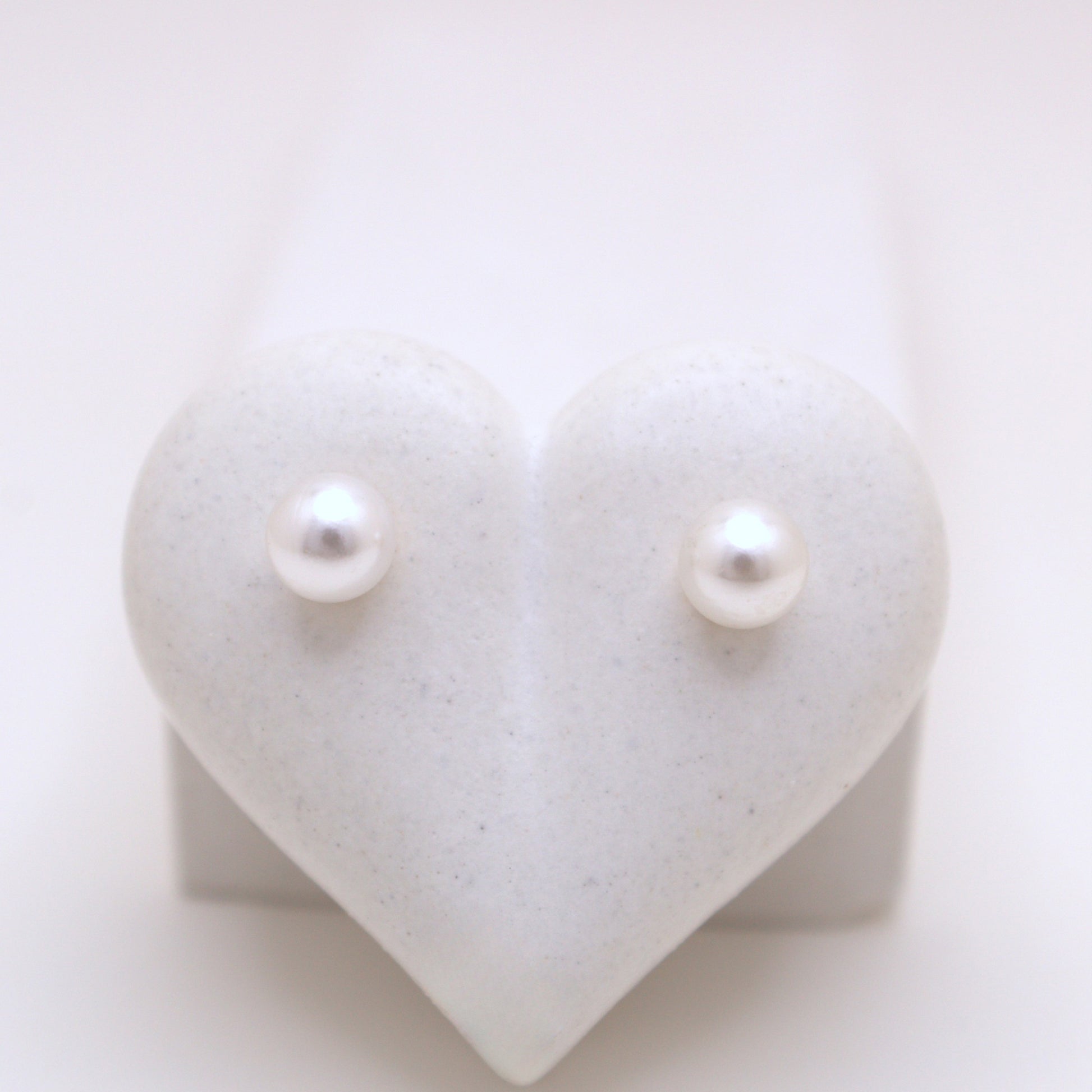 Pearl earrings on a heart-shaped white stand