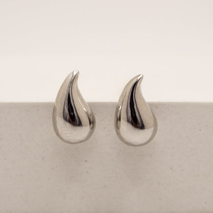 Pair of silver teardrop-shaped earrings on a light gray surface.