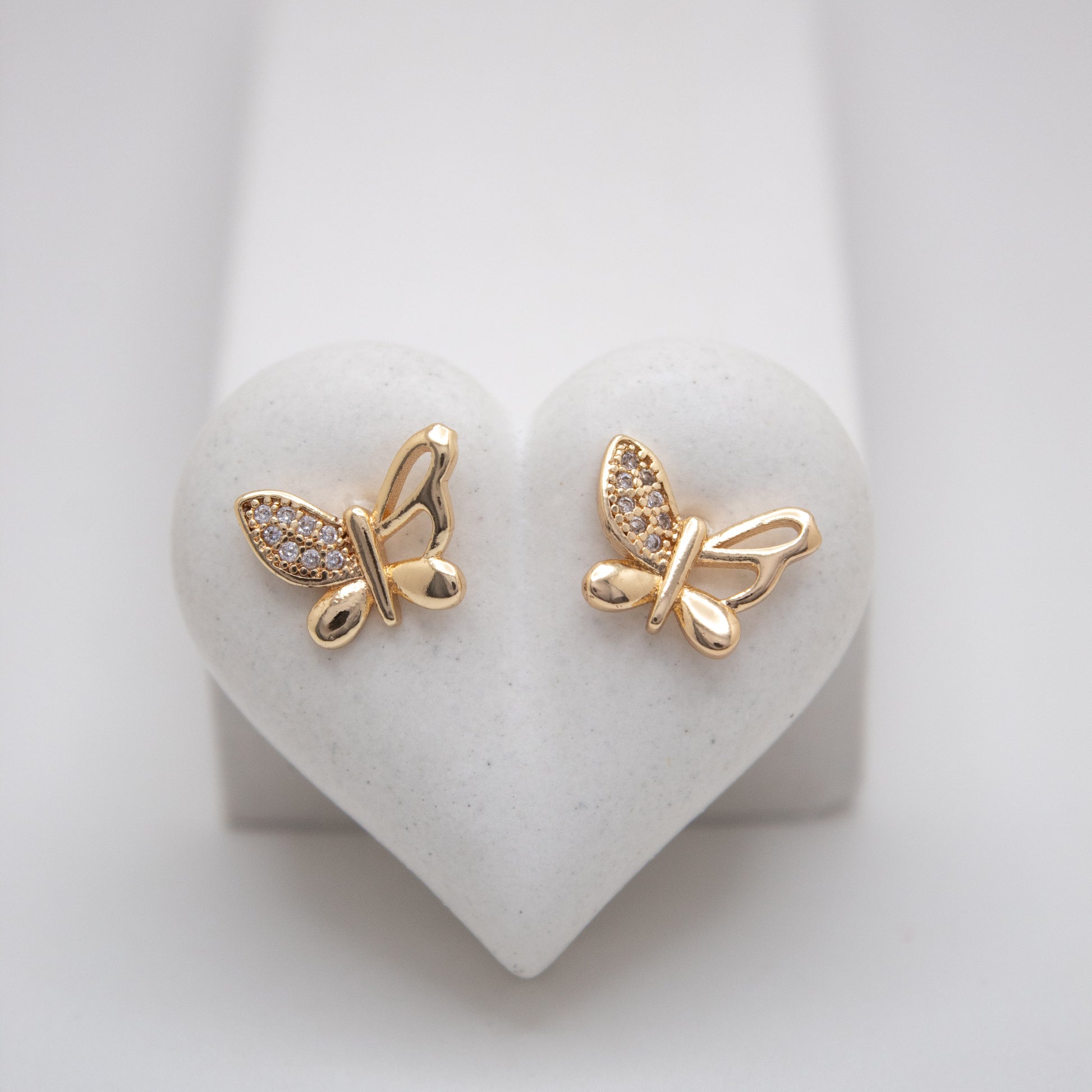 Gold butterfly earrings on a heart-shaped white stand