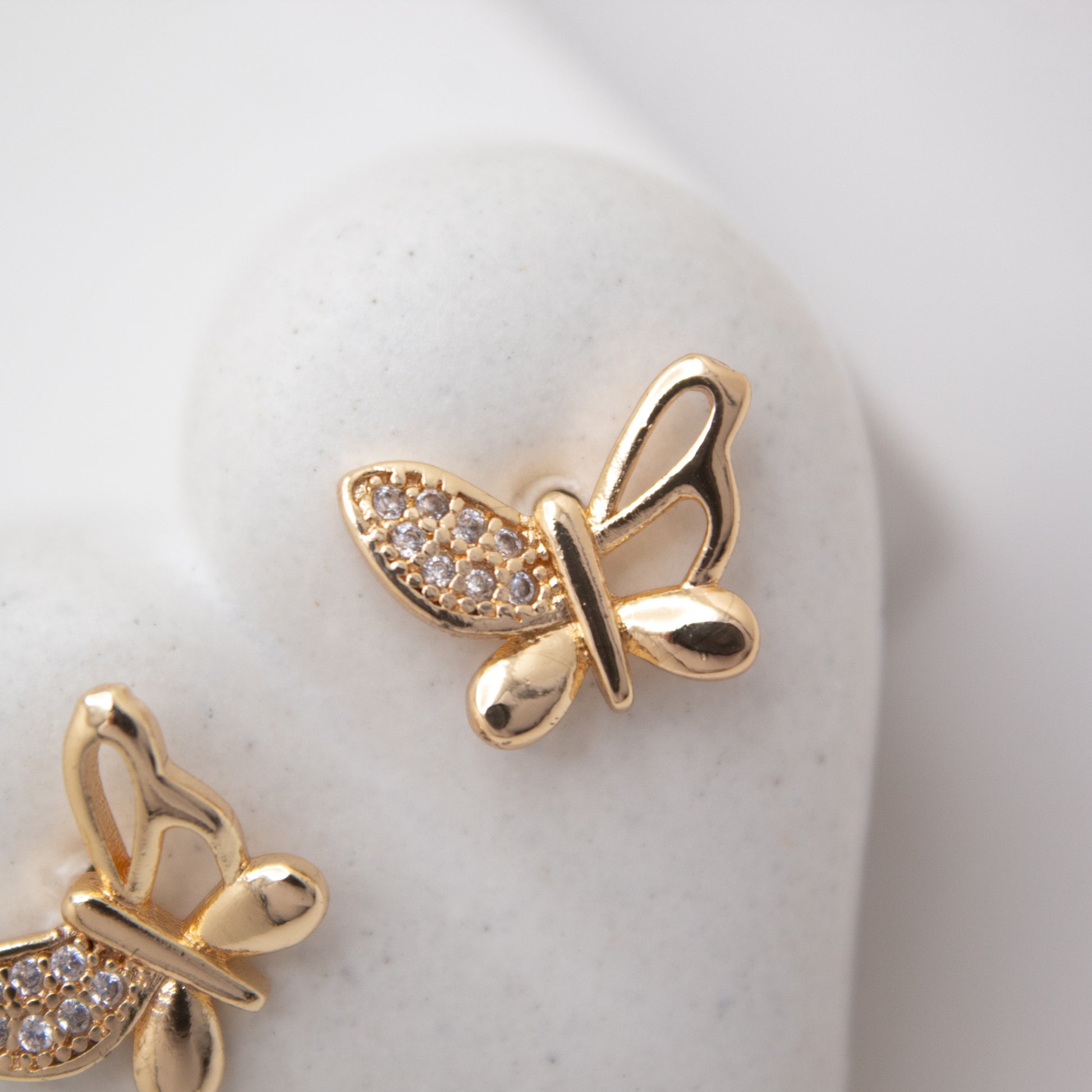 Gold butterfly earrings with gemstones on a white background