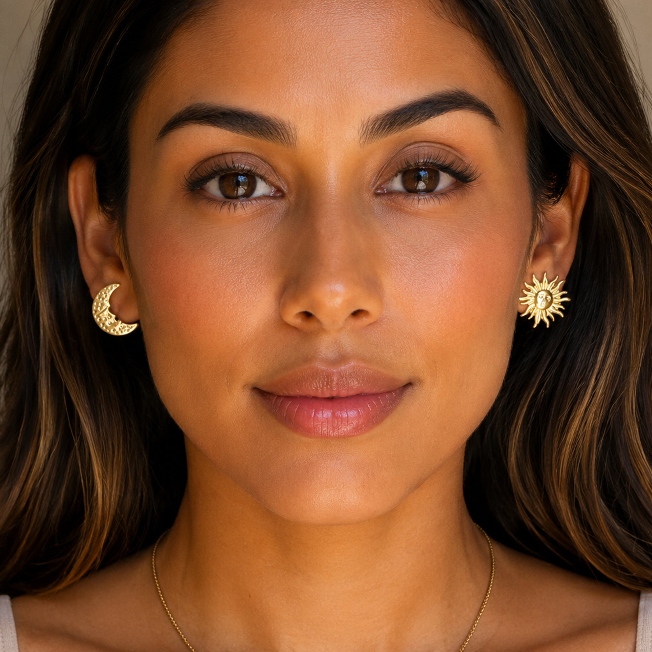 Woman wearing gold earrings with a neutral background