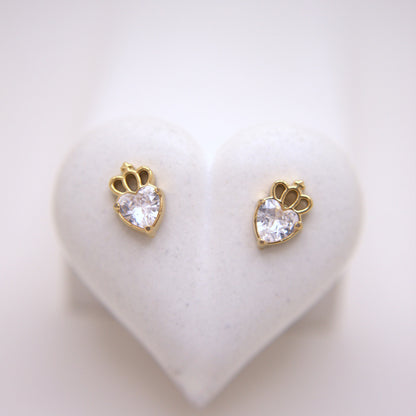 Heart-shaped earrings with clear gemstones on a heart-shaped stand.