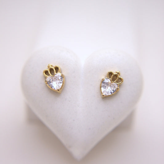 Heart-shaped earrings with clear gemstones on a heart-shaped stand.