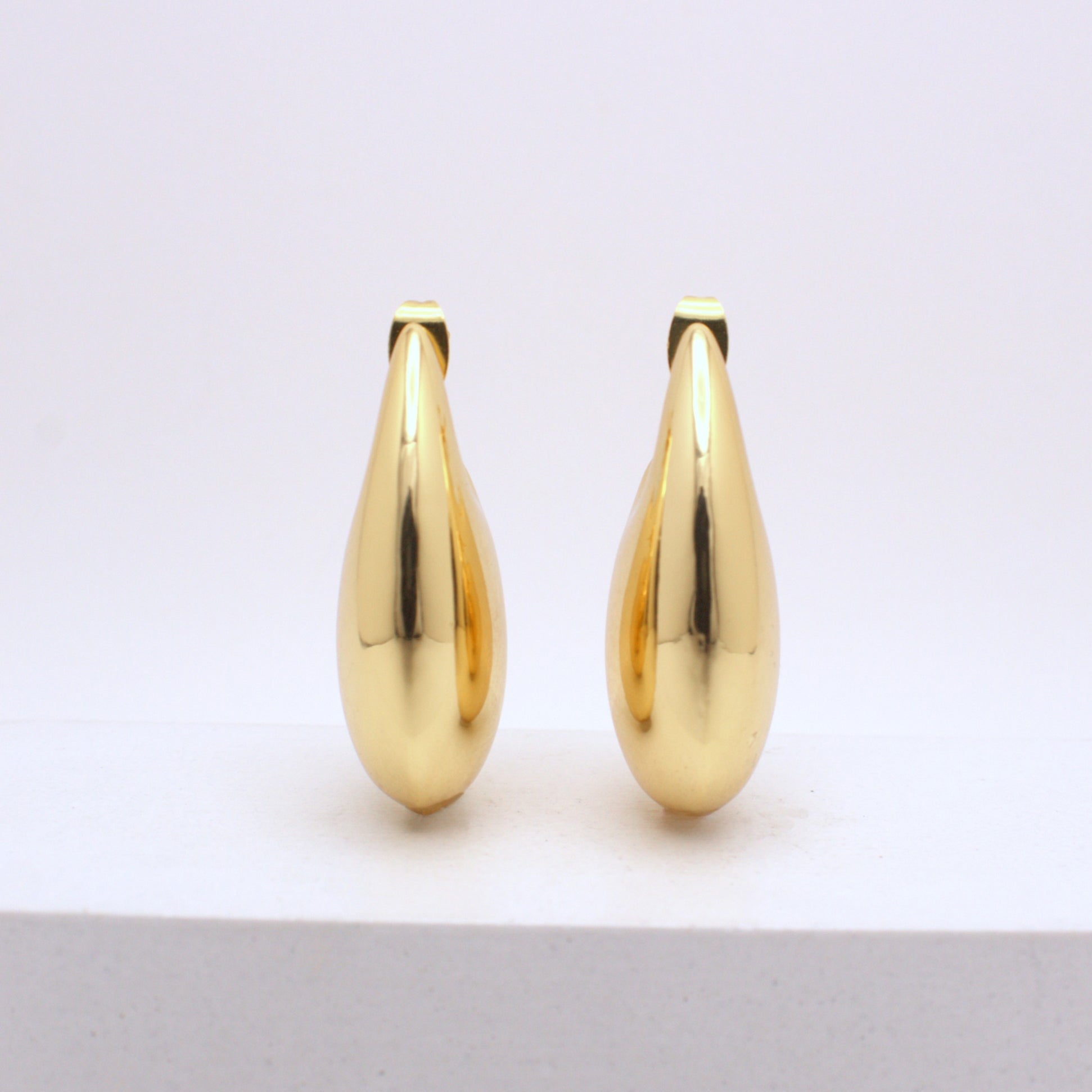 Pair of gold teardrop-shaped earrings on a white background