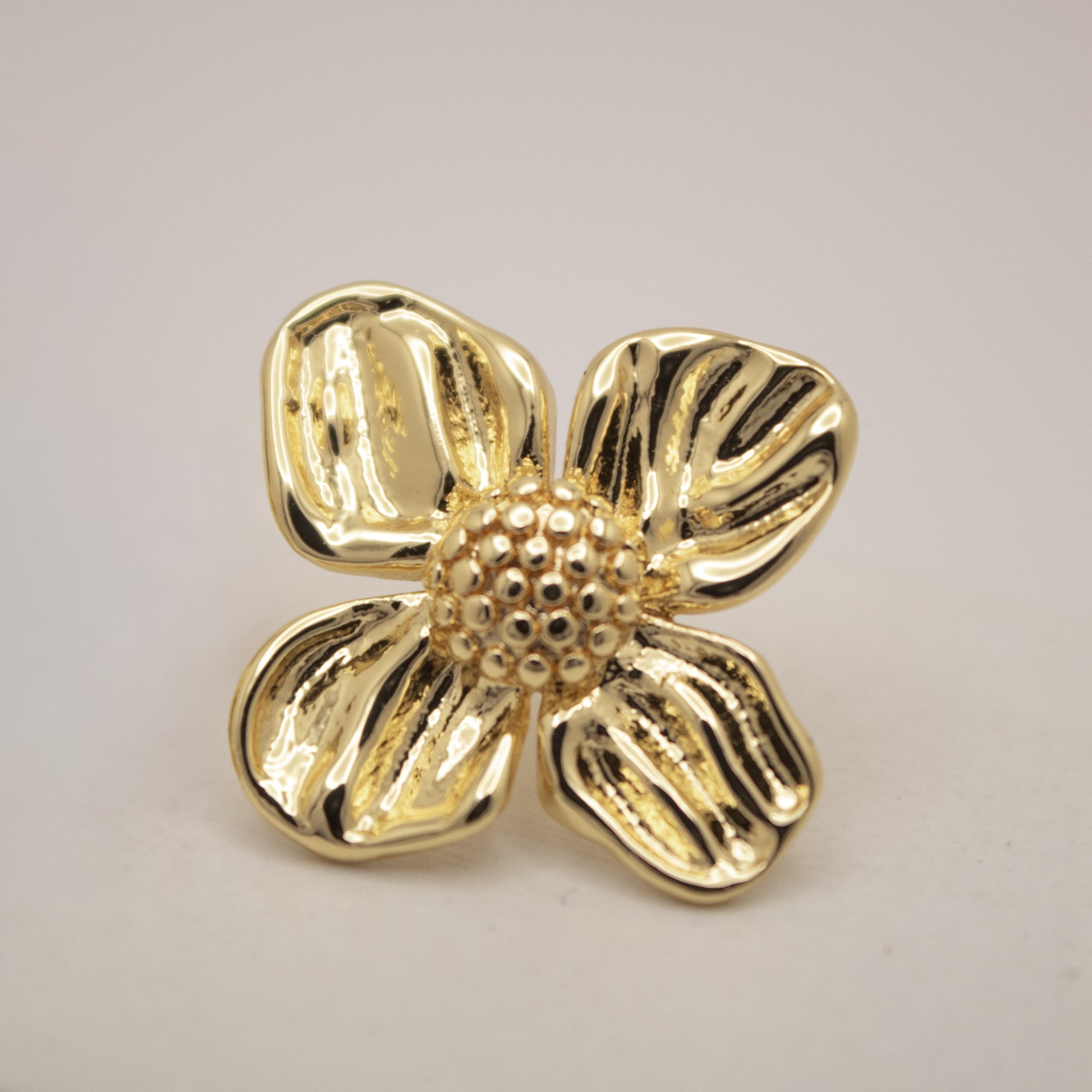 Gold flower-shaped brooch on a light gray background