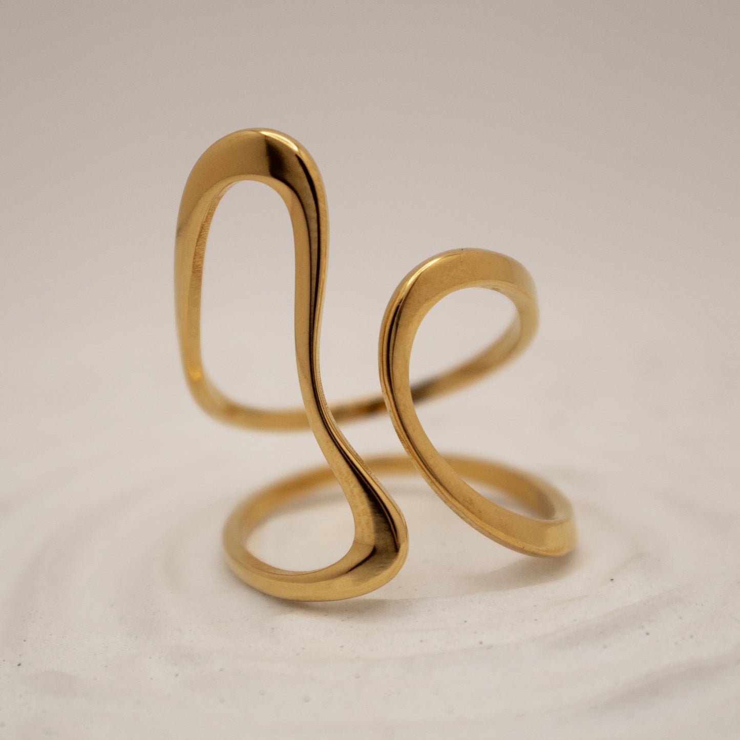 Gold spiral ring on a beige background