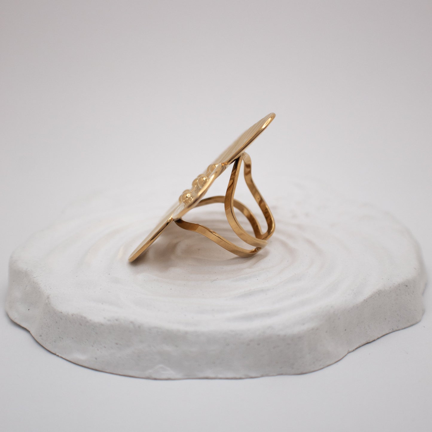 Gold ring on a white stone surface with a plain background