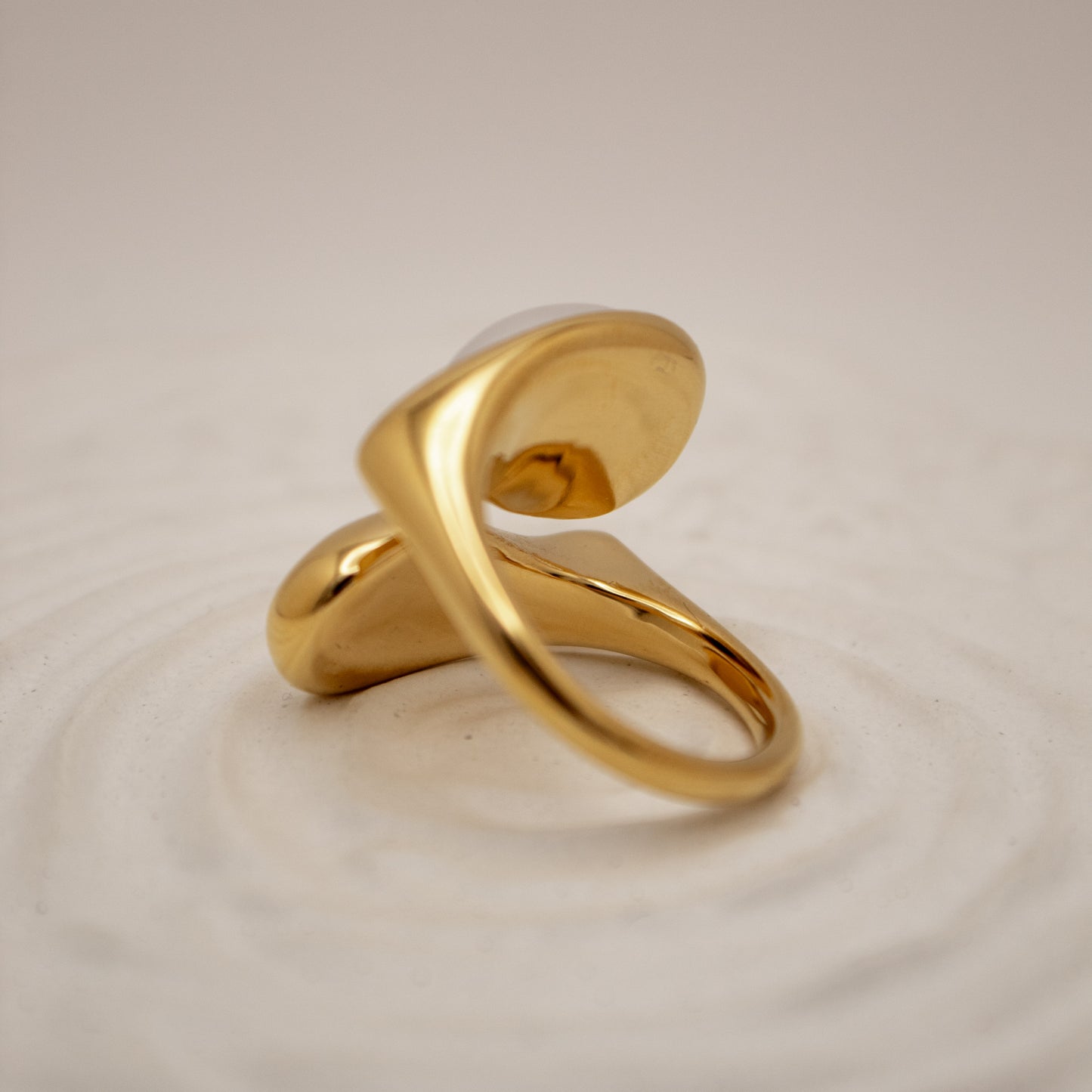 Gold ring on a textured beige background