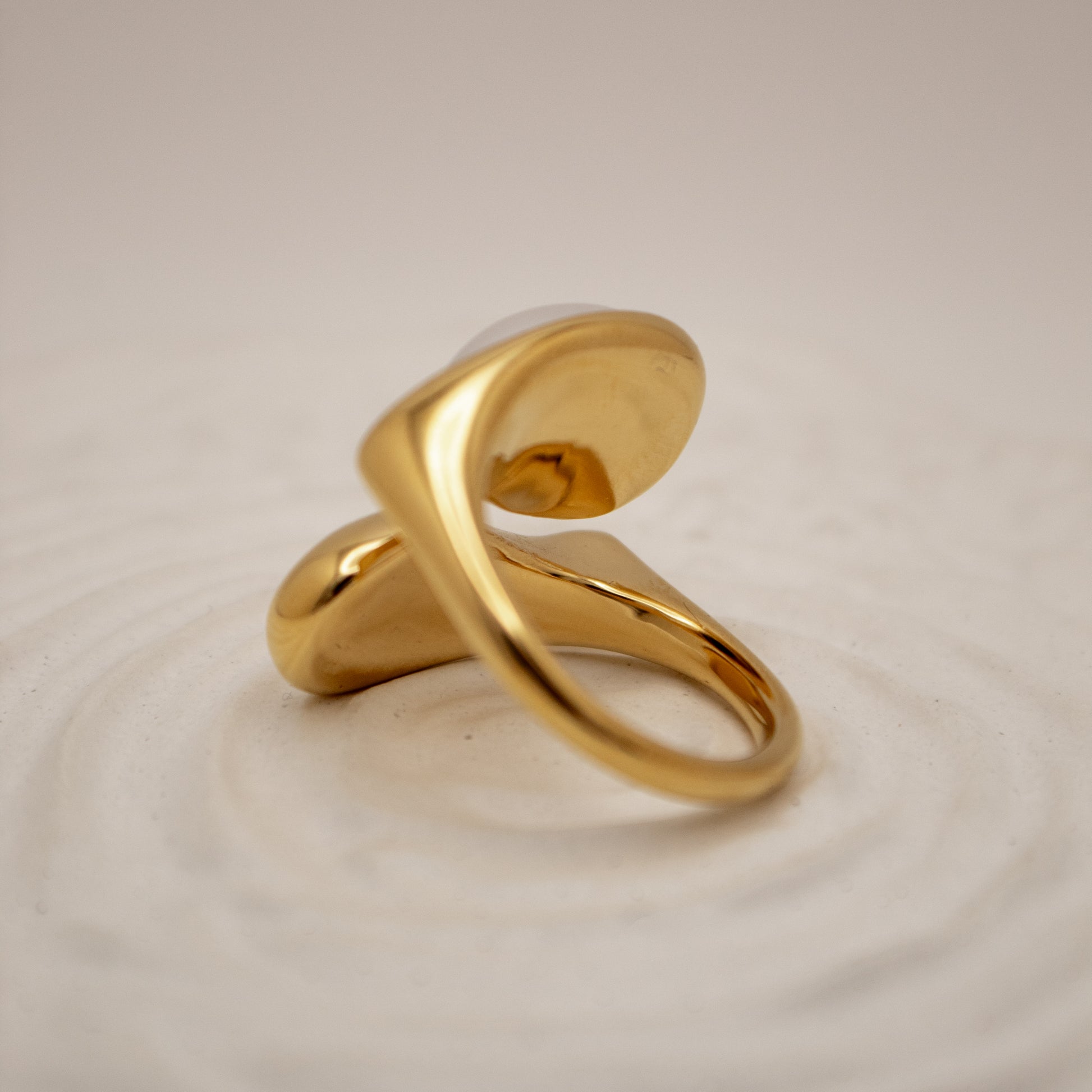 Gold ring on a textured beige background