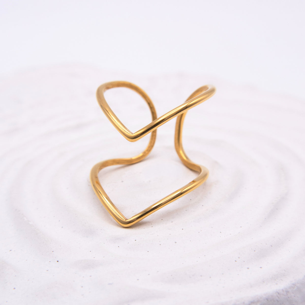 Open sculptural gold ring with flowing curved lines.