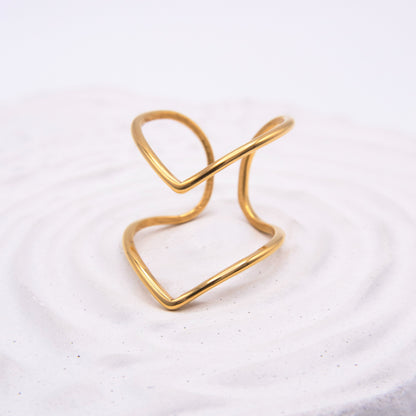 Open sculptural gold ring with flowing curved lines.