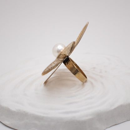 Gold and pearl ring on a white surface with water ripples