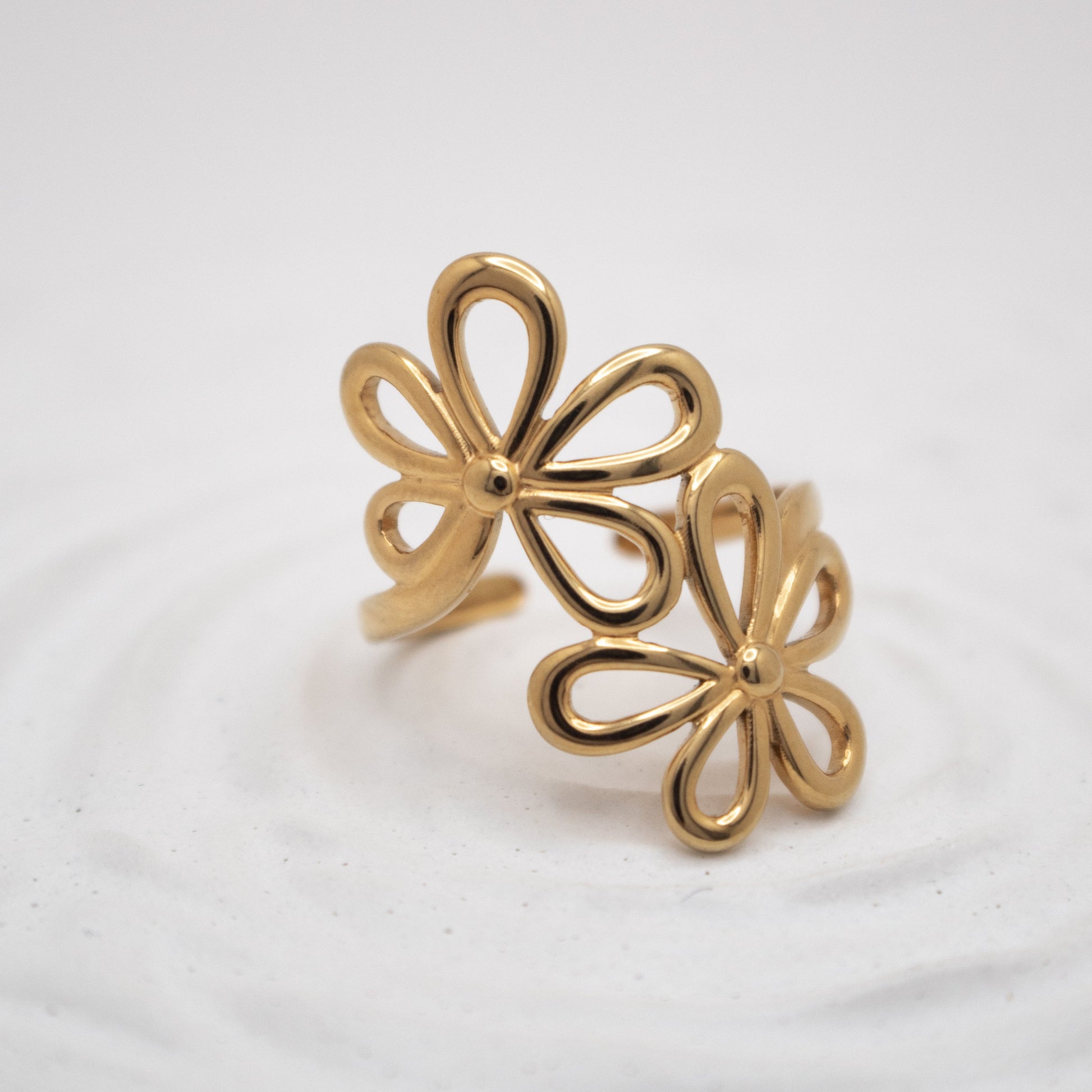 Gold flower-shaped earrings on a light gray background