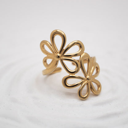 Gold flower-shaped earrings on a light gray background