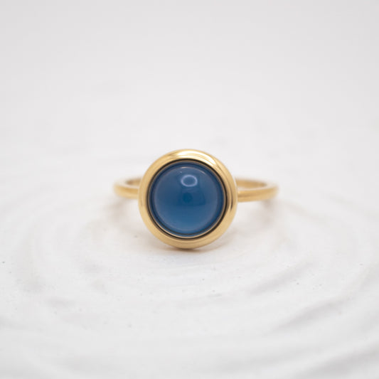 Gold ring with a blue stone on a white background