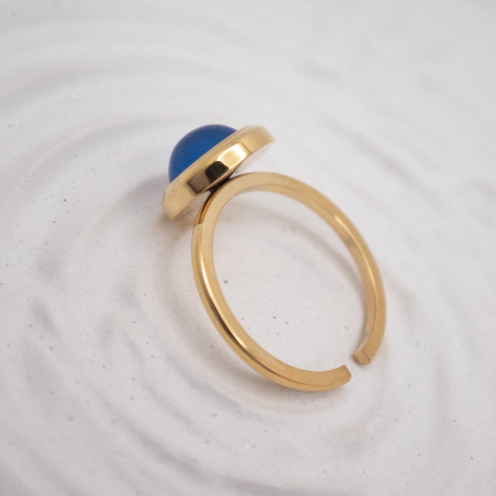 Gold ring with a blue gemstone on a white background