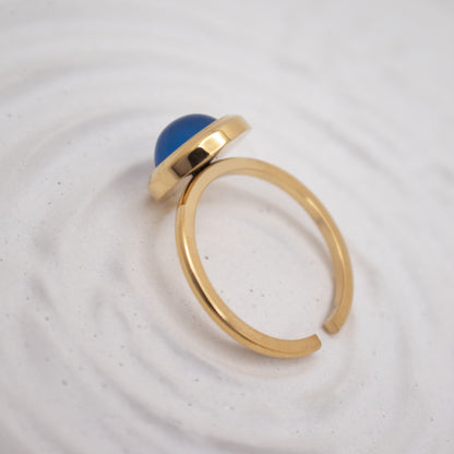 Gold ring with a blue gemstone on a white background