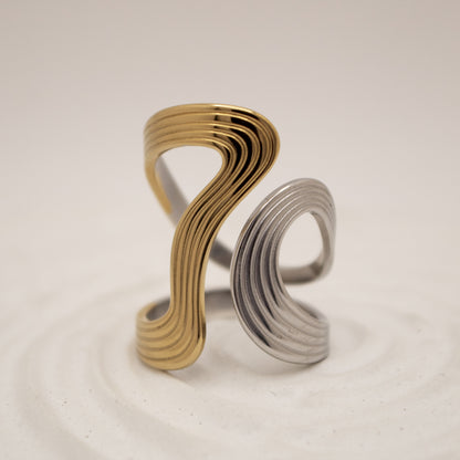 Gold and silver spiral ring on a beige background